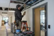 Installer tracing access control cable above a commercial corridor
